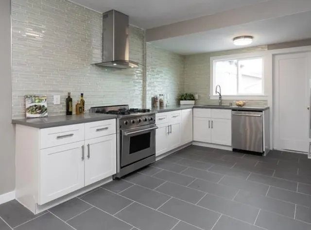 a kitchen with stainless steel appliances a stove a sink and white cabinets