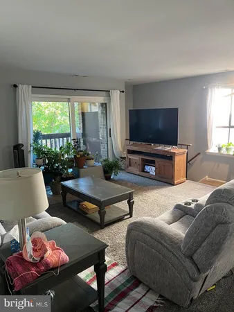 a living room with furniture a flat screen tv and a large window