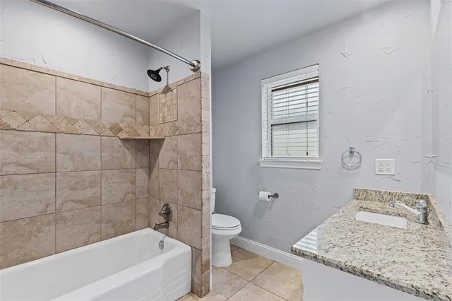 a bathroom with a granite countertop sink a toilet and bathtub