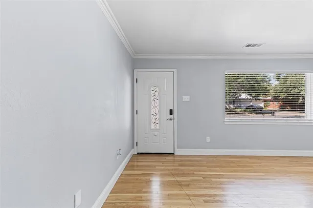 a view of an empty room with window and wooden floor