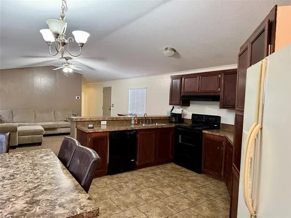 a kitchen with stainless steel appliances granite countertop wooden cabinets a refrigerator a stove a sink and dishwasher