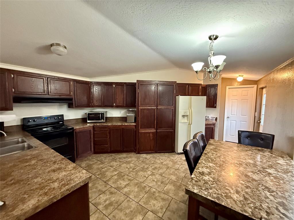 9455 County Road 189 Bangs, TX 76823 - Photo 21 of 40 a kitchen with stainless steel appliances granite countertop wooden cabinets a refrigerator a stove a sink and dishwasher