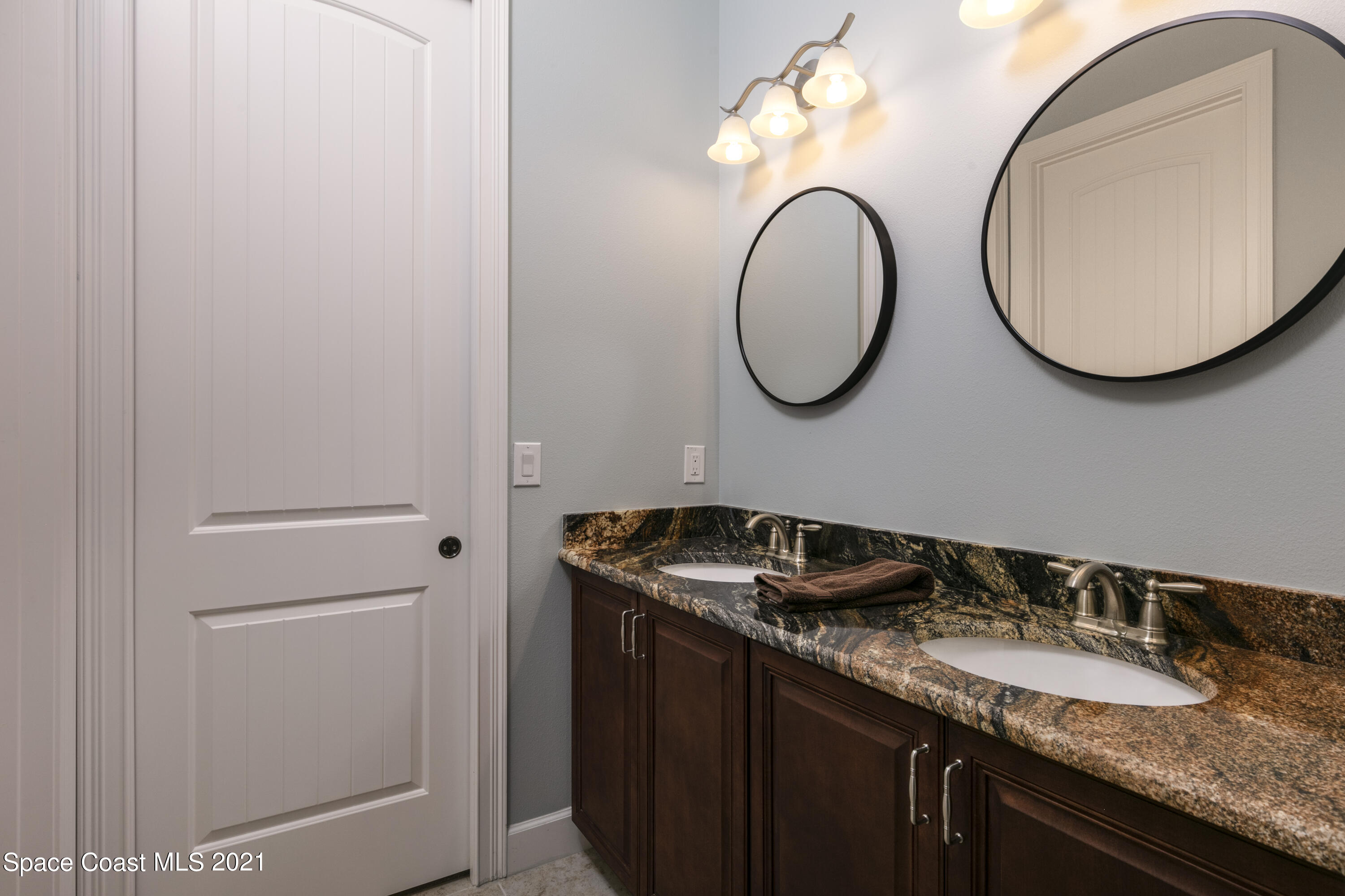 4584 Preservation Circle Melbourne, FL 32934 - Photo 13 of 34 a bathroom with a granite countertop double vanity sink and a mirror