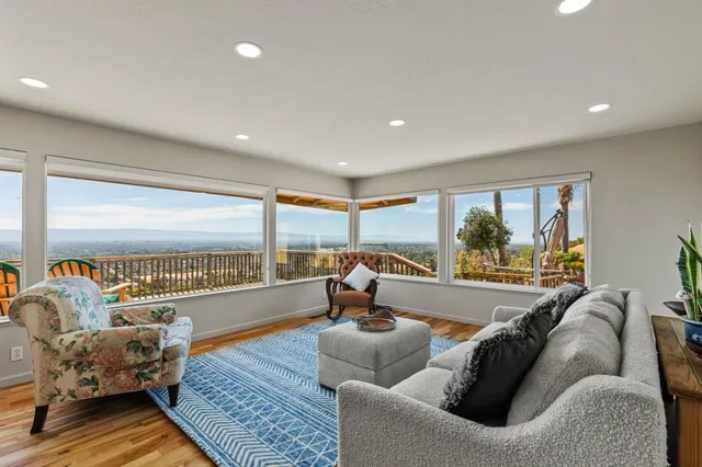 a living room with furniture a floor to ceiling window and wooden floor
