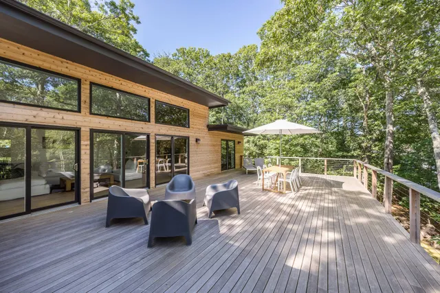 a view of a patio with couches table and chairs under an umbrella with wooden floor