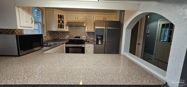 a kitchen with stainless steel appliances granite countertop a refrigerator and a stove top oven