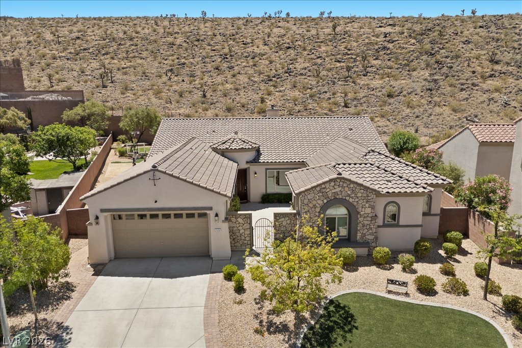2125 De Rouge Avenue Henderson, NV 89044 - Photo 93 of 96 Elegant stone and stucco home nestled against a rugged hillside, featuring a manicured front yard.