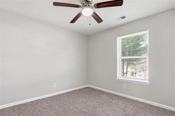 an empty room with a window and a fan
