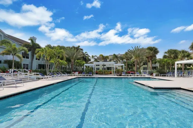 a view of a swimming pool with lawn chairs and a yard