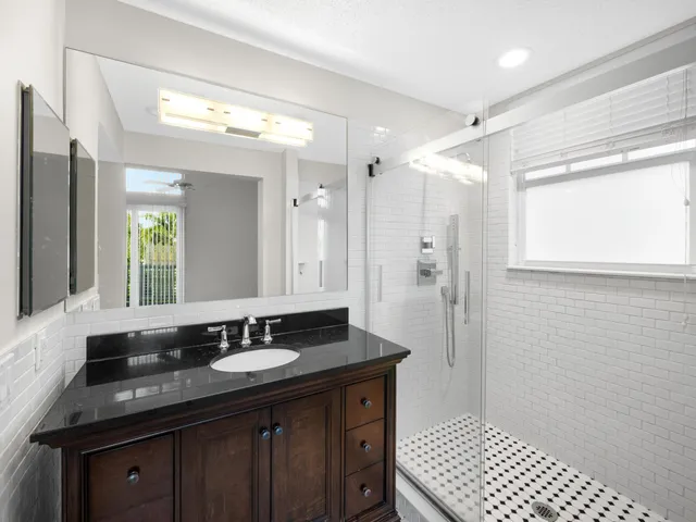 a bathroom with a granite countertop sink a mirror and a shower