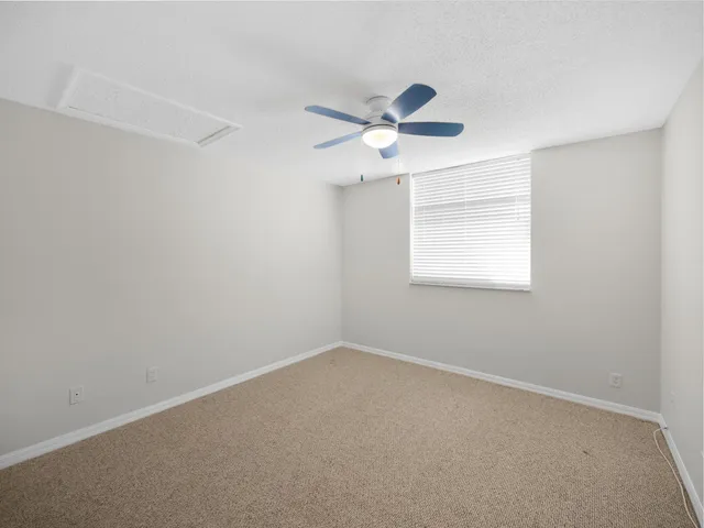 an empty room with a window and a fan