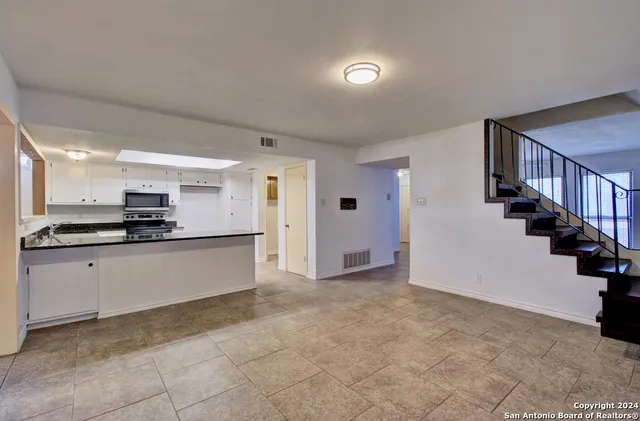 a large white kitchen with stainless steel appliances granite countertop a refrigerator and a stove top oven