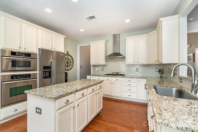 a kitchen with kitchen island granite countertop a sink stove and refrigerator