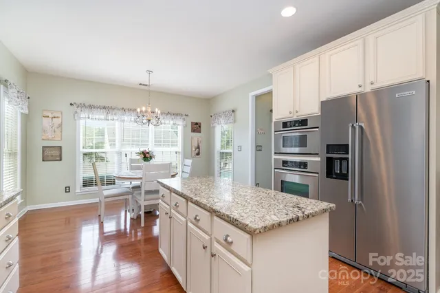 a kitchen with stainless steel appliances granite countertop a refrigerator a stove and a wooden floors