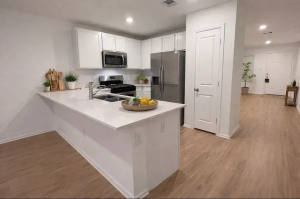 a kitchen with a refrigerator a stove top oven a sink dishwasher and wooden floor