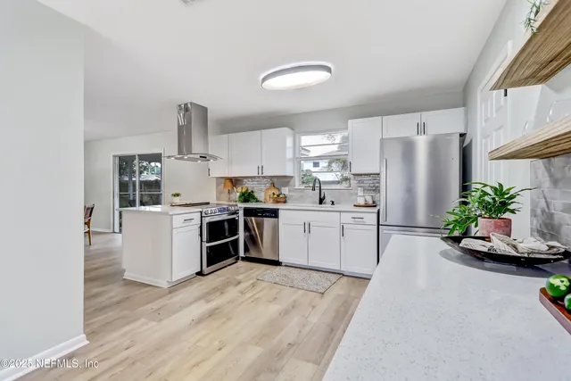 a kitchen with stainless steel appliances a sink a refrigerator and a counter top space