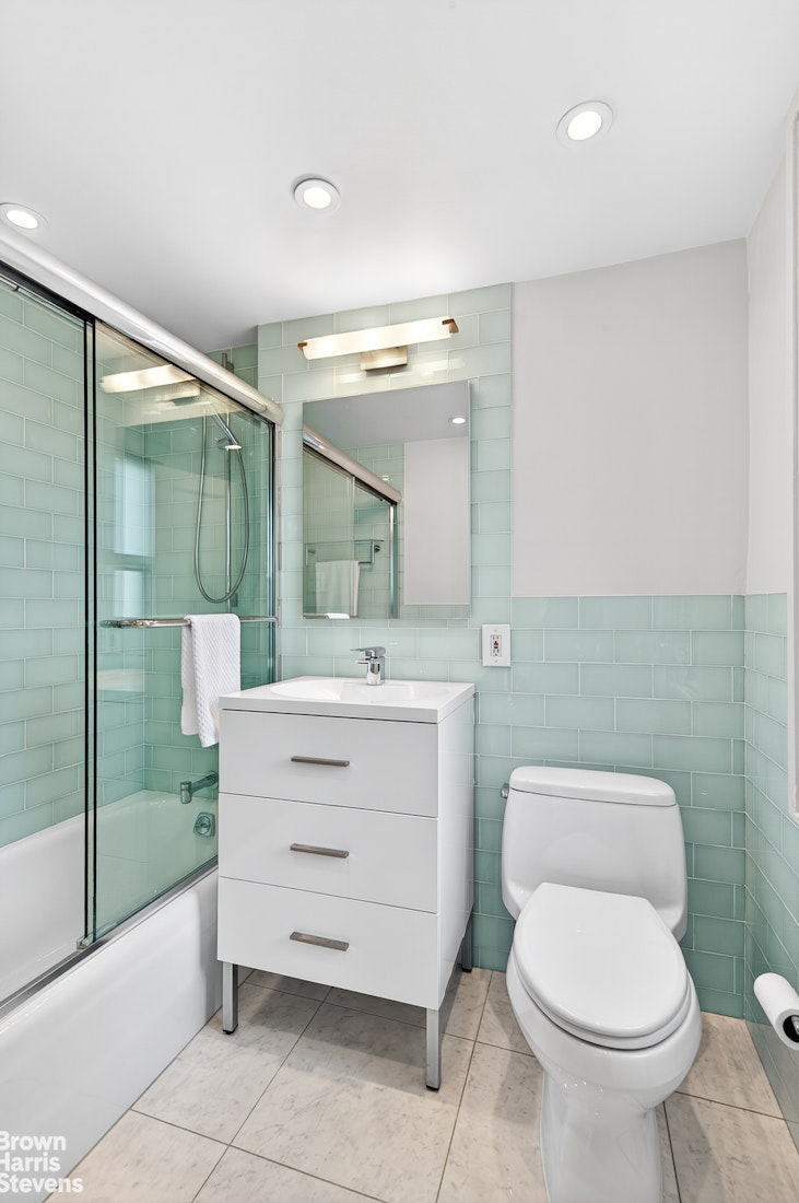 167 East 67th Street, Unit 8A Manhattan, NY 10065 - Photo 11 of 19 a bathroom with a sink a toilet a mirror and shower
