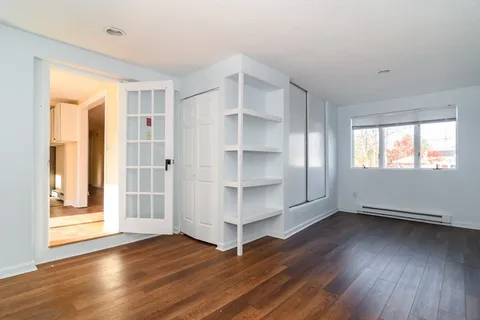 a view of an empty room with window and wooden floor