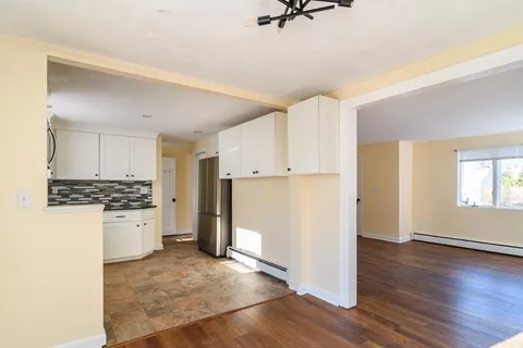 a kitchen with a refrigerator a stove top oven a sink and white cabinets with wooden floor