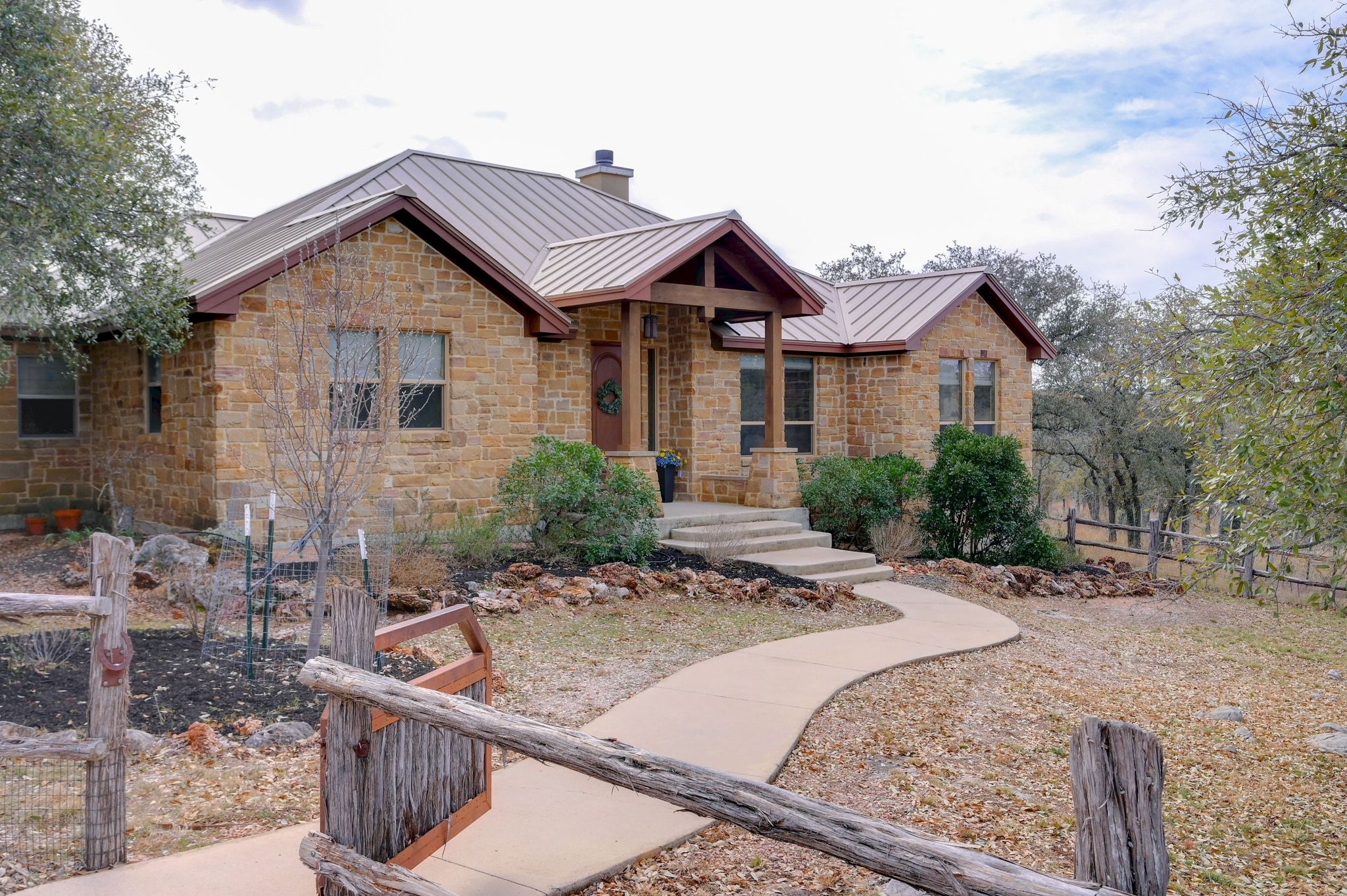 2551 Wolf Creek Ranch Road Burnet, TX 78611 - Photo 2 of 40 View of front of home featuring a standing seam roof, stone siding, and a chimney