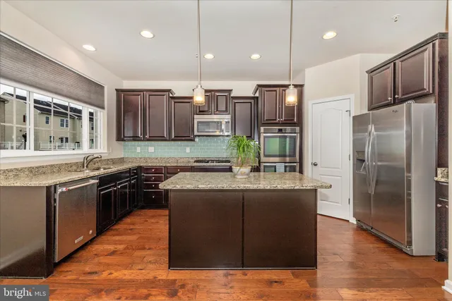 a kitchen with stainless steel appliances granite countertop a refrigerator a stove top oven a sink and dishwasher