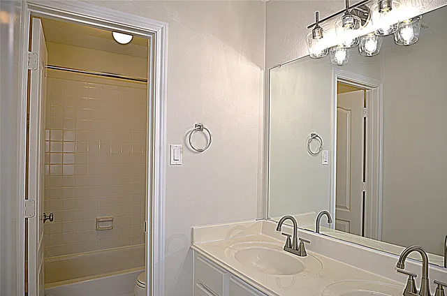 a bathroom with a granite countertop shower sink vanity and mirror