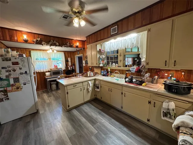 a kitchen with a sink appliances cabinets and a large window
