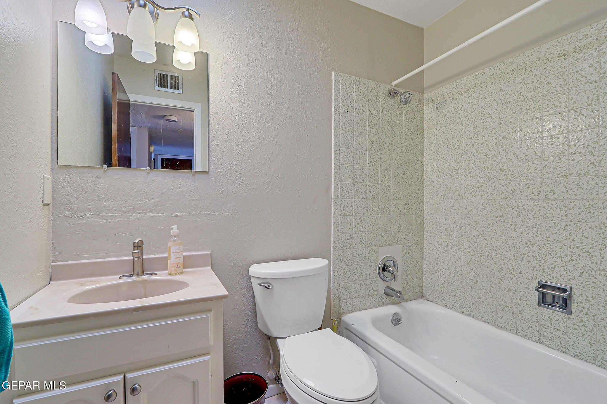 9108 Morelia Road El Paso, TX 79907 - Photo 26 of 35 a bathroom with a toilet a sink a mirror and a bathtub