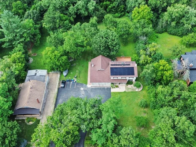 an aerial view of a house with a yard and a large tree