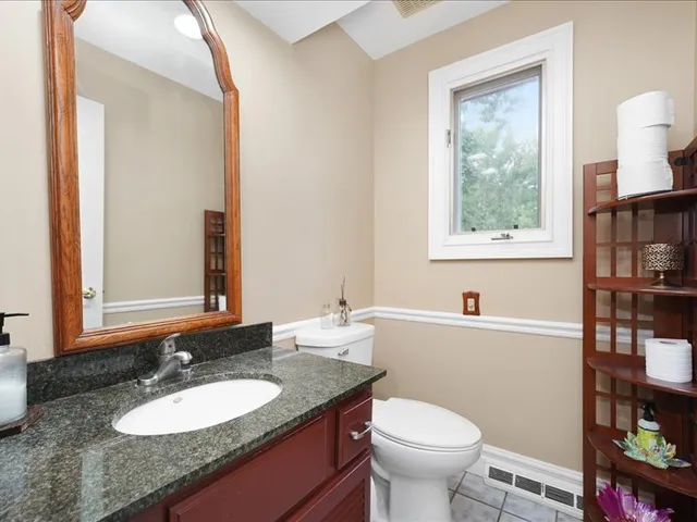 a bathroom with a granite countertop toilet a sink and a mirror