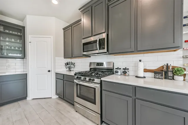 a kitchen with stainless steel appliances granite countertop a stove a sink and a microwave