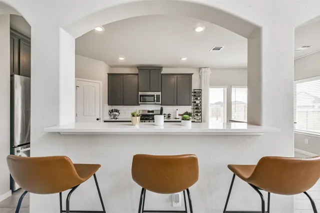 a kitchen with stainless steel appliances granite countertop a dining table chairs and a refrigerator