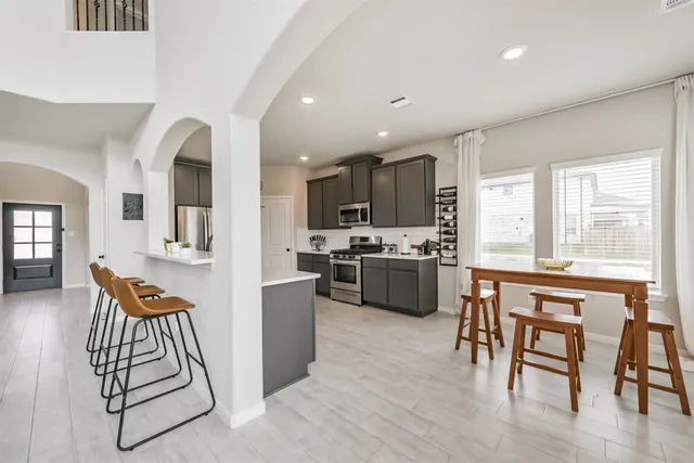 a kitchen with stainless steel appliances kitchen island granite countertop a stove a sink a refrigerator and a dining table with wooden floors