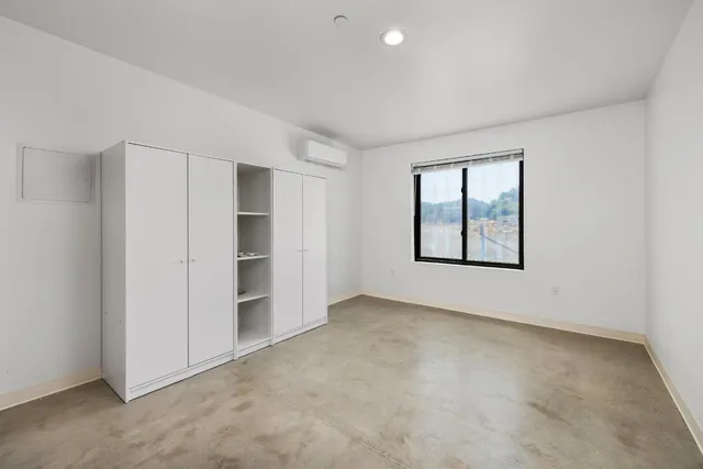 a view of an empty room with closet and a window