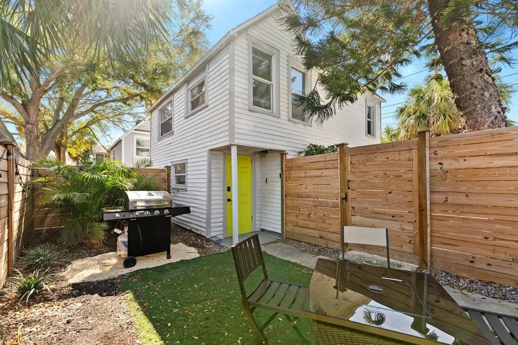 a view of a patio with table and chairs a barbeque and a large tree