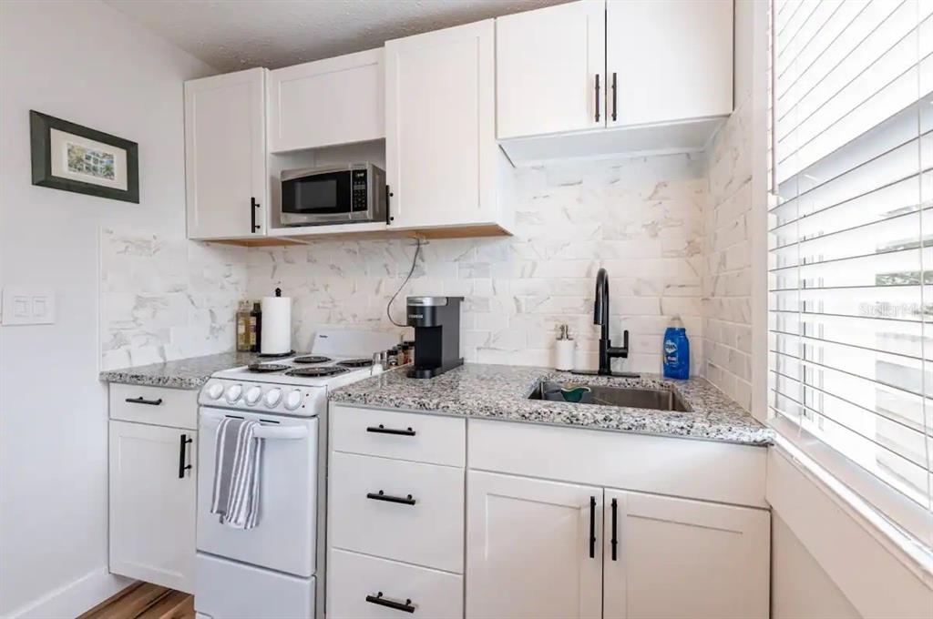 3320 18th Street North St. Petersburg, FL 33713 - Photo 22 of 28 a kitchen with stainless steel appliances granite countertop a sink stove top oven and microwave