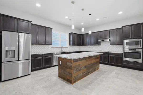 a kitchen with kitchen island granite countertop wooden cabinets and stainless steel appliances