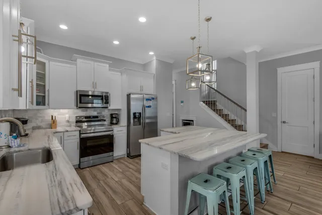 a kitchen with stainless steel appliances a dining table chairs stove refrigerator and microwave