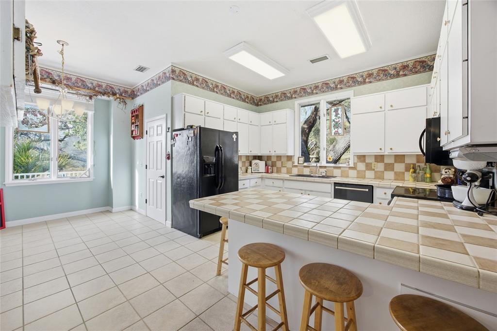 10400 Southeast 101st Avenue Road Belleview, FL 34420 - Photo 16 of 59 a kitchen with stainless steel appliances kitchen island granite countertop a table chairs and a refrigerator