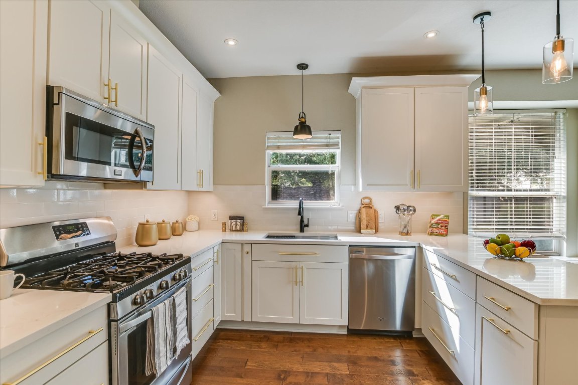 3231 Foothills Trail Round Rock, TX 78681 - Photo 7 of 25 Kitchen with stainless steel appliances, built in microwave oven, dishwasher, a gas range, hanging pendant light fixtures, new quartz counter tops and a peninsula.
