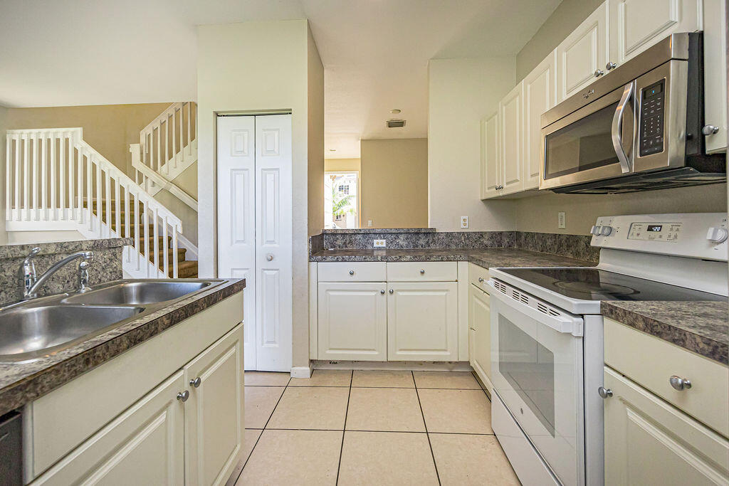 970 Tortuga Drive Riviera Beach, FL 33404 - Photo 14 of 37 a kitchen with stainless steel appliances granite countertop a sink and a stove