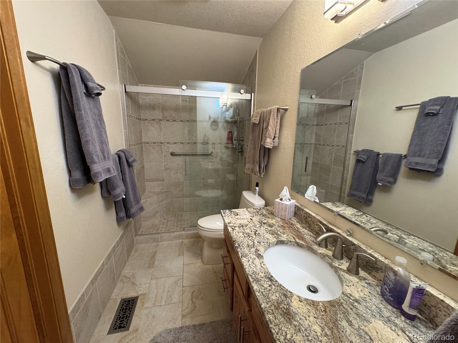 70 Highpoint Circle Black Hawk, CO 80422 - Photo 18 of 37 a bathroom with a granite countertop sink a mirror and shower