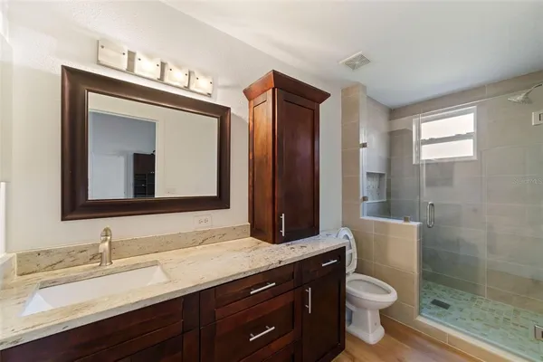 a bathroom with a granite countertop sink mirror and toilet