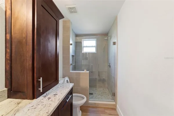 a bathroom with a granite countertop sink a toilet and shower
