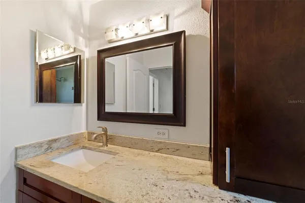 a bathroom with a granite countertop sink and a mirror
