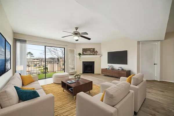 a living room with furniture floor to ceiling window hardwood floor and a flat screen tv