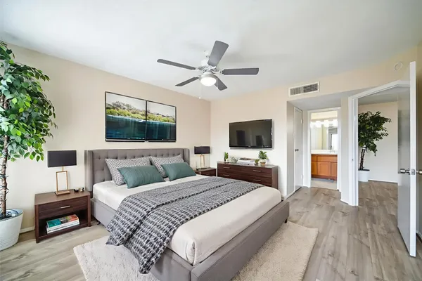 a bedroom with a large bed a flat tv screen and a chandelier