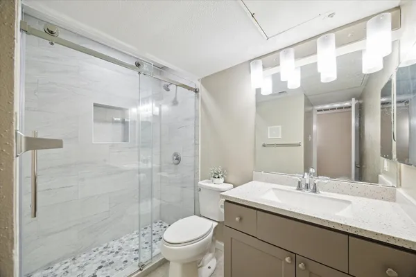 a bathroom with a granite countertop sink a toilet and shower