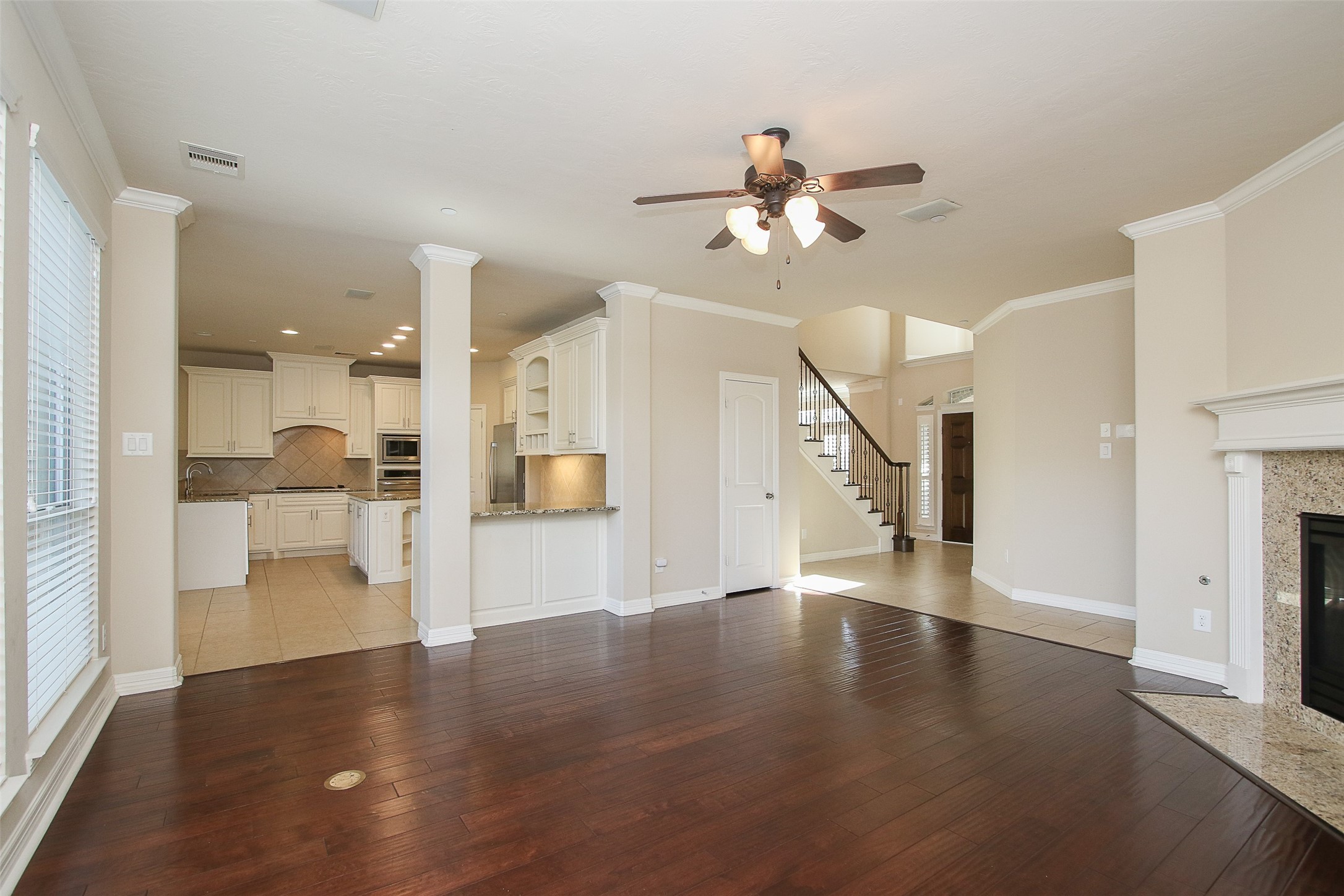 11722 Spriggs Way Houston, TX 77024 - Photo 15 of 49 a view of an empty room and a kitchen with wooden floor