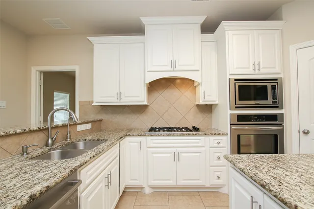 a kitchen with granite countertop white cabinets and stainless steel appliances